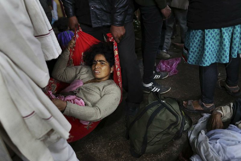 An injured Indian woman who survived a stampede on a railway platform is carried away at the main railway station in Allahabad, India, on Sunday. 
