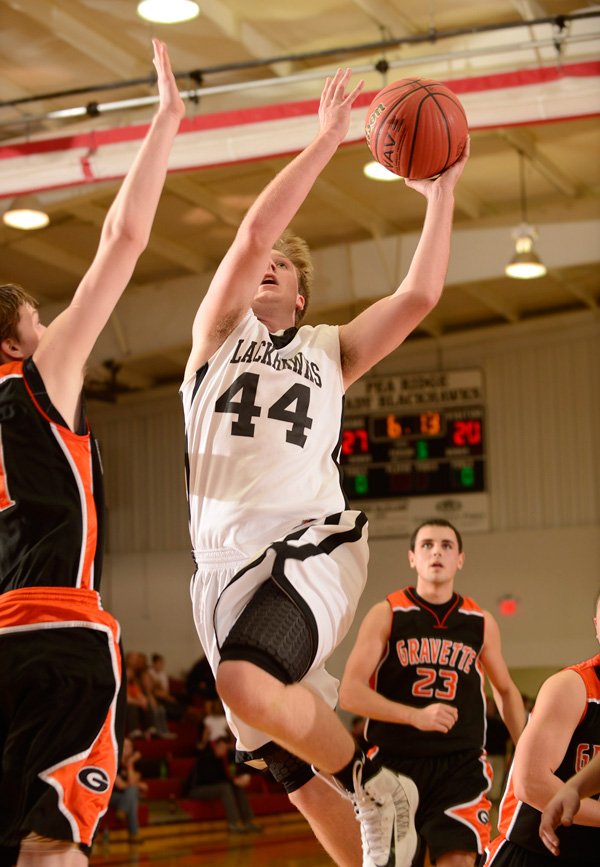 Jacob Hall of Pea Ridge takes the ball to the basket Jan. 29 under pressure from Gravette’s Carson Pollreis in Pea Ridge.