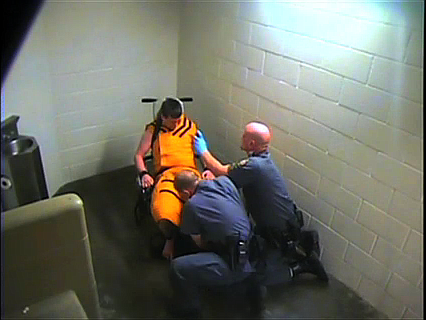A frame from a video showing Benton County jailers restraining and pepper-spraying an inmate.