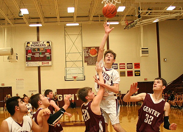 Lincoln junior Dylan McConnell shoots over the heads of Gentry defenders Blake Boyd (25) and Robbie Massie (32) during tournament play in Gentry on Tuesday night.