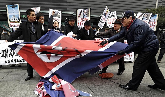 South Korean protesters slit up a North Korean flag during an anti-North Korea rally in Seoul, South Korea, following a nuclear test conducted by North Korea Tuesday, Feb. 12, 2013. North Korea said it successfully detonated a miniaturized nuclear device at a northeastern test site Tuesday, defying U.N. Security Council orders to shut down atomic activity or face more sanctions and international isolation. The signs read " Out, Kim Jong Un." (AP Photo/Lee Jin-man)