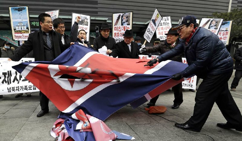 South Korean protesters slit up a North Korean flag during an anti-North Korea rally in Seoul, South Korea, following a nuclear test conducted by North Korea Tuesday, Feb. 12, 2013. North Korea said it successfully detonated a miniaturized nuclear device at a northeastern test site Tuesday, defying U.N. Security Council orders to shut down atomic activity or face more sanctions and international isolation. The signs read " Out, Kim Jong Un." (AP Photo/Lee Jin-man)