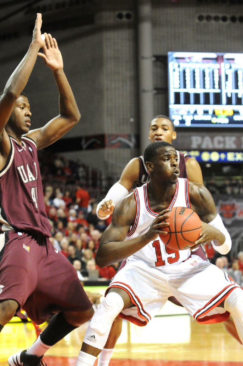 Arkansas State forward Brandon Peterson (right) looks to pass the ball around two UALR defenders during the first half of the Red Wolves’ 86-62 victory over the Trojans on Thursday at the Convocation Center in Jonesboro. 