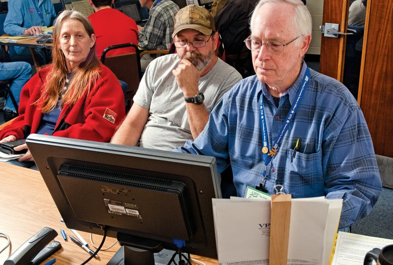 Barbara and Russell Easter, left, look on as Gene Alden does their taxes during a free tax-prearation event held by the AARP at the Hughes Center in Russellville.