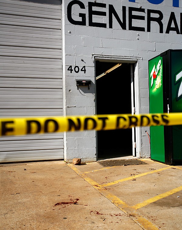 Splattered blood is seen on the pavement Thursday outside the entrance to Latino Mechanica on Campbell Drive in Springdale. Springdale Police found a man dead from multiple stab wounds in the parking lot of the shop Wednesday night. 