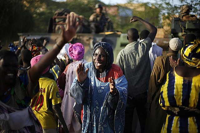 A Malian women cheers Malian soldiers arriving in a convoy at the military base in Timbuktu, Mali, Saturday Feb. 2, 2013. French President Francois Hollande visited the fabled city for two hours, twenty days after the start of operation Serval. (AP Photo/Jerome Delay)