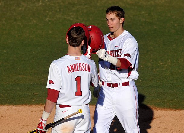 Arkansas first baseman Eric Fisher is greeted by teammate Brian Anderson as he crosses home plate after a solo home run in the third inning of Friday afternoon's season opener at Baum Stadium in Fayetteville. 