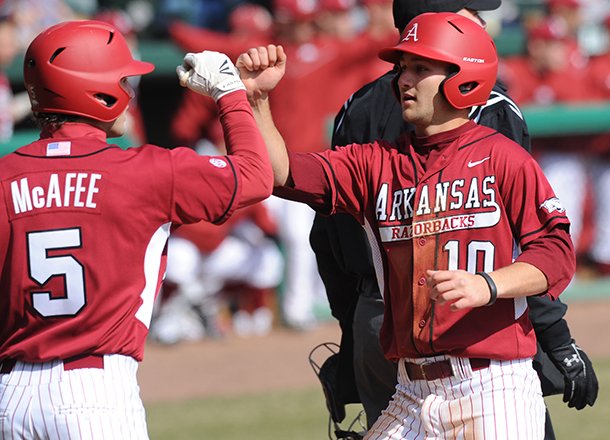 Arkansas' Joe Serrano (10) is congratulated at the plate by Brett McAfee after scoring a run and recording and RBI Saturday, Feb. 16, 2013, during the sixth inning of the Hogs' win over Western Illinois at Baum Stadium in Fayetteville.