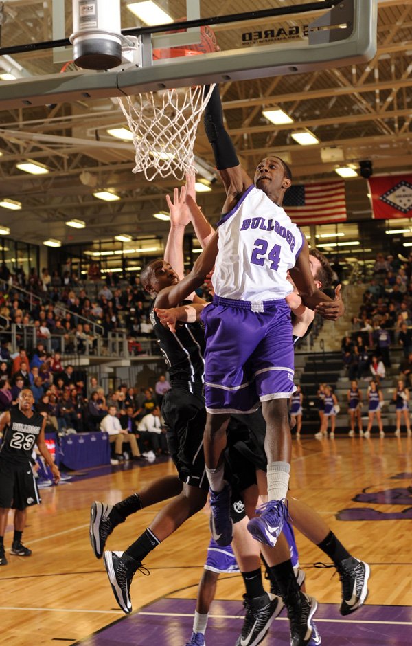 Jawan Smith, a Fayetteville senior guard, dunks a missed field goal attempt over the Springdale defense Friday during the first half of play in Bulldog Gymnasium at Fayetteville. 