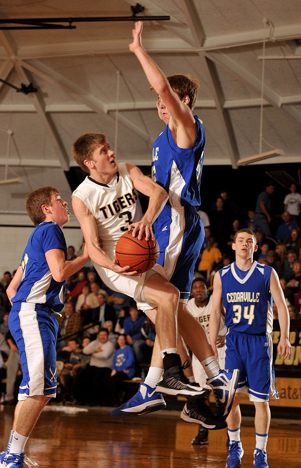 Josh Ferrell of West Fork is fouled by Cedarville defenders Austin Myers and Zach Bradford, right, as he tries to drive to the hoop during Friday’s finals in the 3A-1 West district tournament at West Fork. 