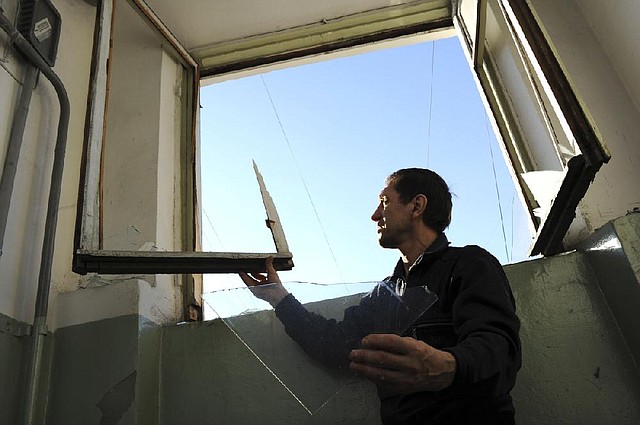 A local resident repairs a window broken by a shock wave from a meteor explosion in Chelyabinsk, about 1500 kilometers (930 miles) east of Moscow,  Friday, Feb. 15, 2013. A meteor that scientists estimate weighed 10 tons (11 tons) streaked at supersonic speed over Russia's Ural Mountains on Friday, setting off blasts that injured some 500 people and frightened countless more. (AP Photo/Boris Kaulin)