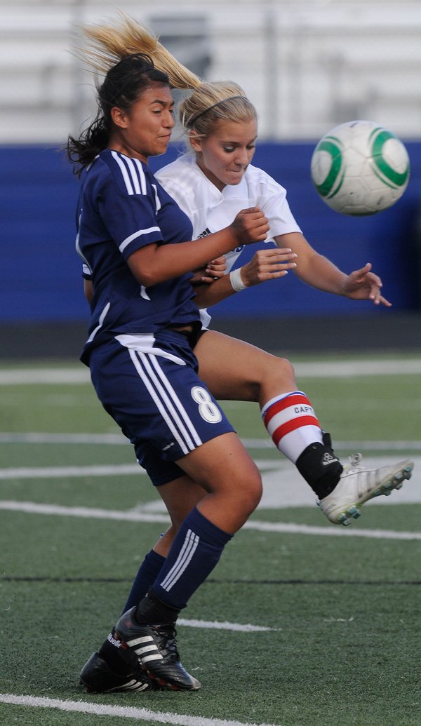 Springdale Har-Ber’s Ana Martinez, left, fights for the ball with Rogers High’s Kate Schmandt last year at Mountie Stadium in Rogers. The Lady Wildcats will open its 2013 season on Tuesday against Bentonville at Jarrell Williams Bulldog Stadium in Springdale. 