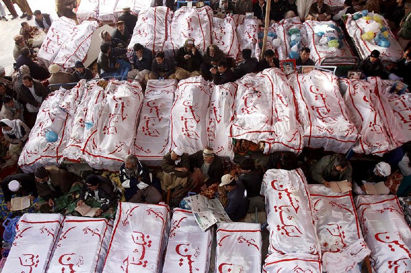 Pakistani Shiite Muslims sit in protest Monday with the dead bodies of their family members killed in Saturday’s bombing in Quetta. The shroud writing reads “We are ready Hussian.” 