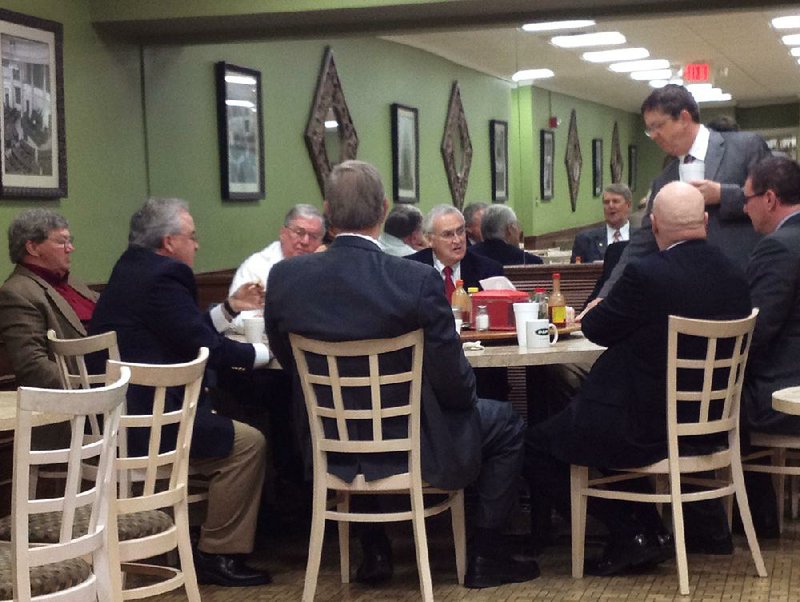 Legislators, lobbyists and various staff members gather for food and fellowship at the big round table reserved for them in the cafeteria in the basement of the state Capitol. 