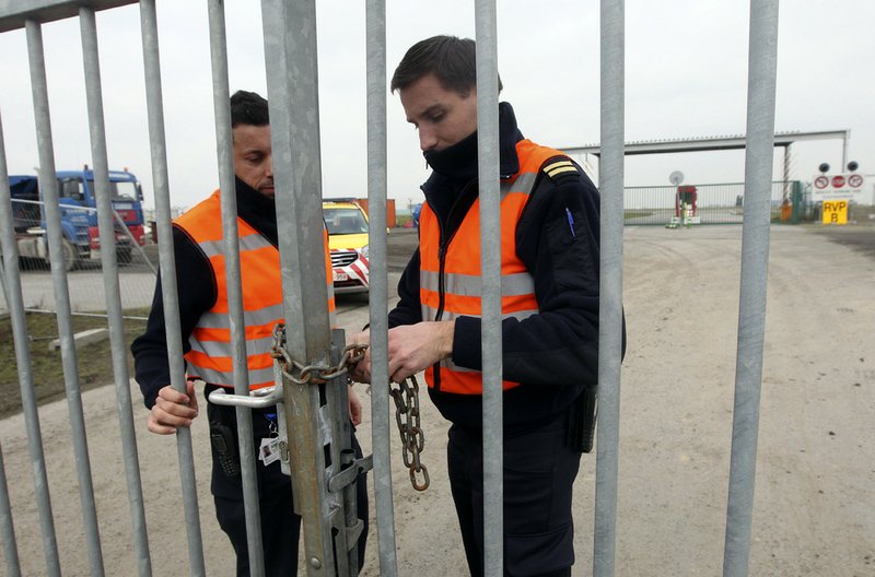 Two airport police officers use a chain to lock a gate which leads to the airport tarmac, at Brussels international airport, Tuesday, Feb. 19, 2013. Eight masked gunmen made a hole in a security fence at Brussels' international airport, drove onto the tarmac and snatched some $50 million worth of diamonds from the hold of a Swiss-bound plane without firing a shot, authorities said Tuesday. 