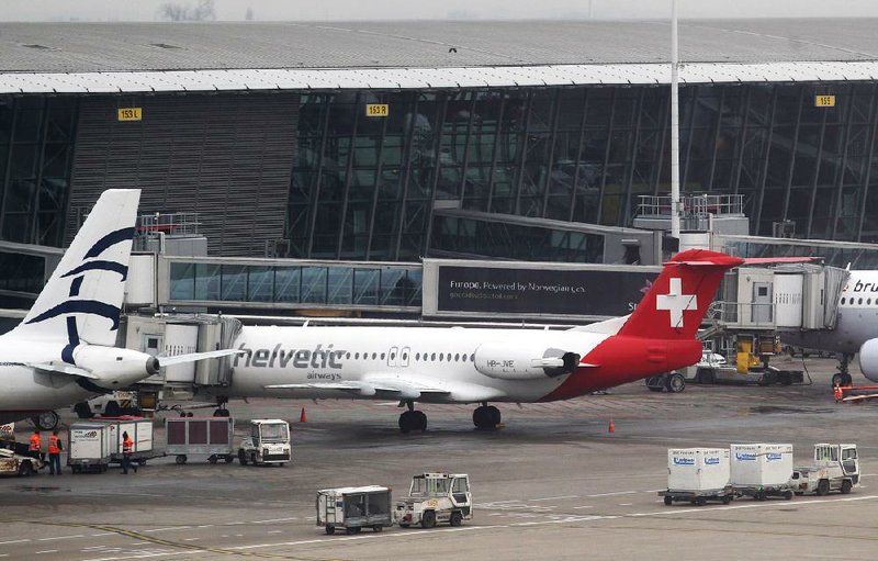 Baggage carts make their way past a Helvetic Airways aircraft from which about $50 million worth of diamonds were stolen on the tarmac of Brussels international airport Tuesday, Feb. 19, 2013. Eight armed and masked men made a hole in a security fence at the airport, drove onto the tarmac and snatched the diamonds from the hold of the Swiss-bound plane without firing a shot, authorities said Tuesday. (AP Photo/Yves Logghe)