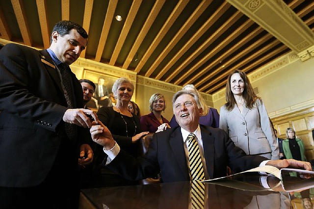 Arkansas Gov. Mike Beebe, center, gives a pen to Rep. David Meeks, R-Conway, left, as Sen. Missy Irvin, R-Mountain View, right, watches during a bill-signing ceremony at the Arkansas state Capitol in Little Rock, Ark., Tuesday, Feb. 19, 2013. The governor signed into law new protections for human trafficking victims.(AP Photo/Danny Johnston)