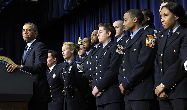 President Barack Obama, accompanied by first responders behind him, speaks in the South Court Auditorium of the Eisenhower Executive Office building on the White House complex in Washington, Tuesday, Feb. 19, 2013, to urge Congress to come up with an alternative plan to avert automatic spending cuts set to kick in on March 1, 2013. (AP Photo/Susan Walsh)