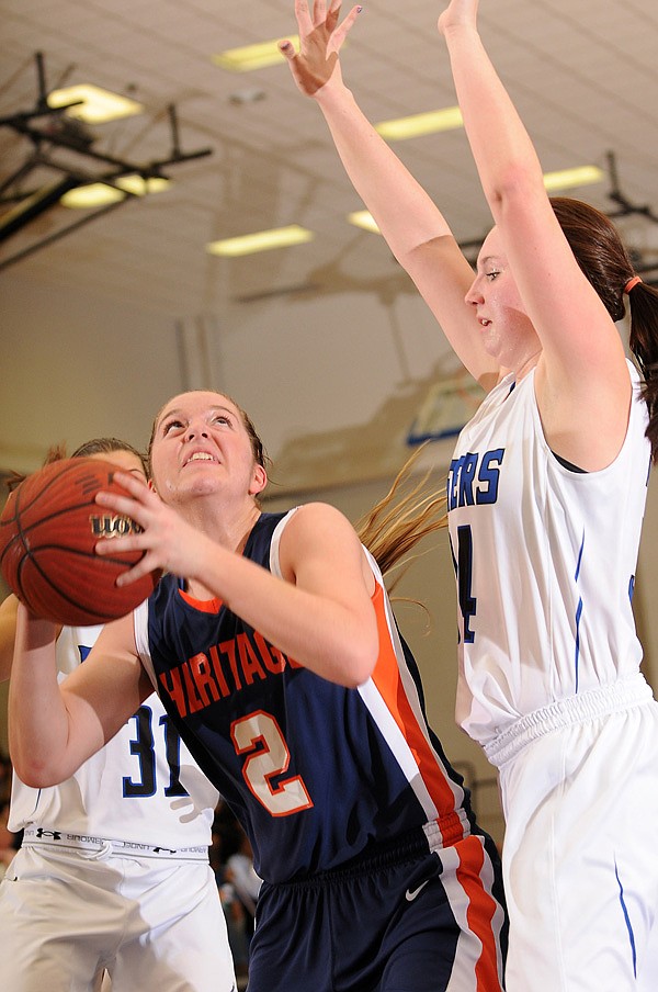 Ashley Ward, left, of Rogers Heritage looks to the basket under pressure from Rogers’ Samantha Warren during Tuesday’s game at King Arena in Rogers. 