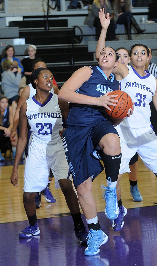 Tayleah Neal, center, of Springdale Har-Ber High School pushes past Alexa Howard, left, and Vanessa Matlock, both of Fayetteville High School, for a layup in the second half of the game Tuesday, Jan. 22, 2013 at Bulldog Arena in Fayetteville. The Lady Wildcats of Har-Ber beat the Lady Bulldogs, 43-28.