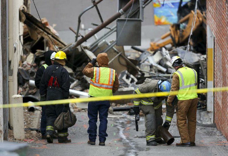 An ATF agent, second from right, looks down a hole in an alley near JJ's restaurant after an explosion and fire tore through the establishment Tuesday evening near the Country Club Plaza Wednesday, Feb. 20, 2013, in Kansas City, Mo. The fire killed one person and injuring over a dozen. (AP Photo/Ed Zurga)