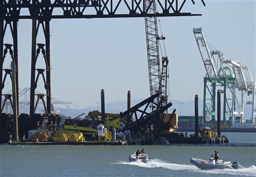 Investigators approach the scene where a crane overturned onto a barge and into San Francisco Bay, seen from Clipper Cove on Treasure Island Thursday, Feb. 21, 2013, in San Francisco. A crane tipped over while working on the new eastern span of the San Francisco-Oakland Bay Bridge on Thursday afternoon, but there were no injuries and nothing leaked into the bay, authorities said. The crane was on a barge underneath the new span helping to remove a temporary support structure and was holding a piece of the structure when it fell around noon Thursday, according to bridge spokesman Andrew Gordon. Gordon said officials are investigating what caused the crane to tip over and whether the new span was damaged at all. The new bridge is expected to open over Labor Day weekend. It will connect Oakland to Treasure Island and replace the eastern span that was damaged during the 1989 Loma Prieta earthquake.