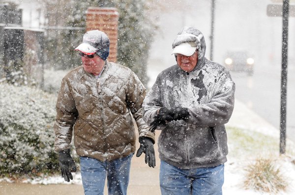 Rick Garrison, left, and Dan Kondik walk in a heavy snowfall Wednesday along Northwest A Street in Bentonville while headed downtown for lunch. The two said they weren’t going to let the winter weather interrupt their daily walk. Bentonville received about an inch of snow as the first round of a two-punch winter storm rolled through Northwest Arkansas before noon. More photos available at photos.nwaonline.com. 