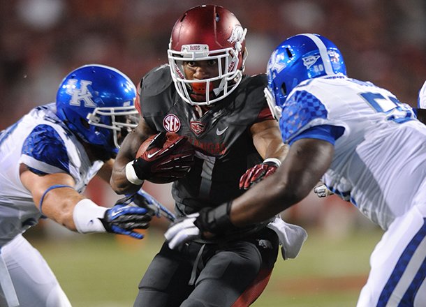 Arkansas running back Knile Davis carries the ball as Kentucky defensive lineman Mike Douglas, right, closes in to make the tackle during the second quarter of play Saturday, Oct. 13, 2012, at Razorback Stadium in Fayetteville.