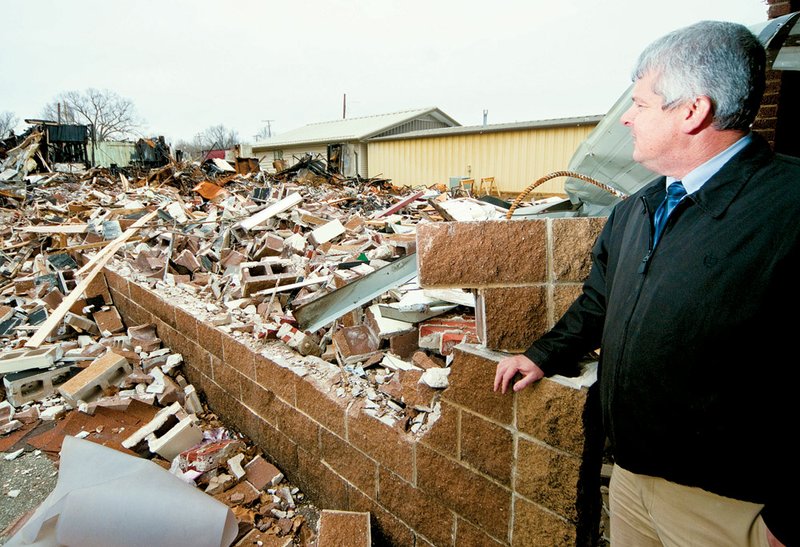 Hector School District Superintendent Walt Davis looks at the rubble of a burned building. The district plans to rebuild on the site.