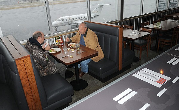Robert Carter, left, and Chris Stecklein eat lunch Thursday at Flaps Down Grill inside the Springdale Municipal Airport. The restaurant is looking in to expanding the size of their space. The restaurant’s capacity is 49 people. 