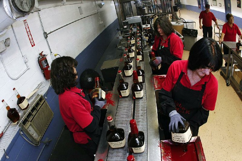 Patti Berry, left front, Roxana Norris, center rear, and Angel Berry, right front, Maker's Mark Distillery Inc. employees, hand dip a bottles of Maker's Mark bourbon whisky with the signature red wax at their distillery in Loretto, Kentucky, U.S., on Tuesday, Jan. 4, 2011. Maker's Mark Distillery Inc. annouced earlier this year that President Bill Samuels Jr. will retire on April 15, 2011, and become chairman emeritus, with his son Rob Samuels replacing him as president. Photographer: John Sommers II/Bloomberg *** Local Caption *** Patti Berry; Roxana Norris; Angel Berry