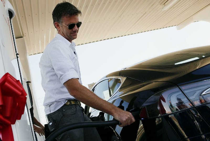 Franz von Holzhausen, chief designer at Tesla Motors Inc., demonstrates the charging system on a Tesla S sedan in Lebec, Calif. The carmaker said it plans to deliver 20,000 of its battery-powered cars this year. 