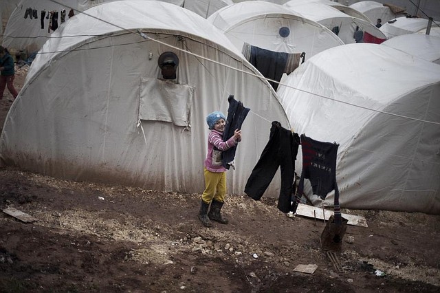 A Syrian girl hangs clothes Friday in the Azaz camp for displaced people, north of Syria’s Aleppo province. According to Syrian activists, the number of people in the camp has grown by 3,000 in the recent weeks because of heavier shelling by government forces. 