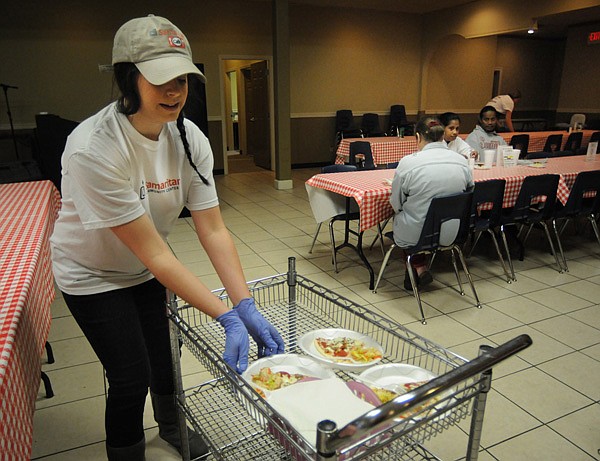 Jessica Sanders reaches for a plate of food Tuesday while serving visitors at the Samaritan Center Cafe in Springdale. 
