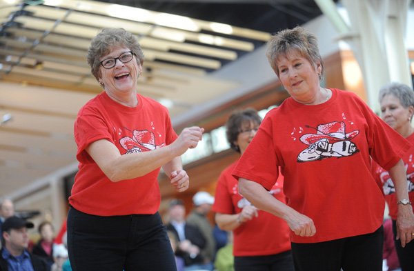 Judy Bailey, left, and Paula Fettig, both members of the Hoot ’N Holler Cloggers, a dance group based in Bella Vista, smile Saturday while performing during the Day of Dance at the Northwest Arkansas Mall in Fayetteville. The event was organized by Washington Regional Medical Center to raise awareness of the importance of heart health and featured several local dance groups. 