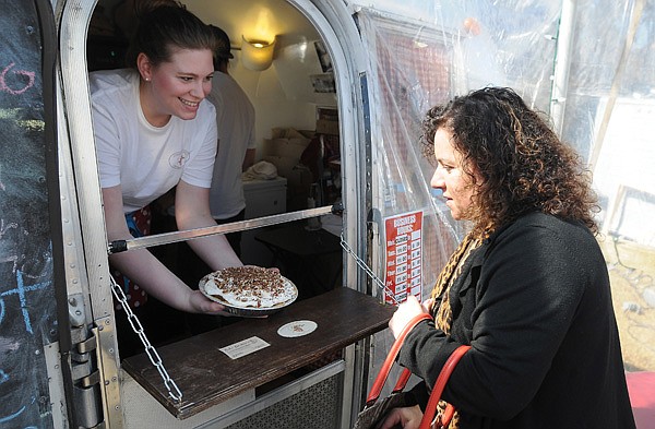 Lauren French, left, holds out a Robert Redford pie for Janette Litaker to inspect Friday at Parks Purity Pie Co. at the Yacht Club, a collection of businesses working out of trailers, on North College Avenue in Fayetteville. 