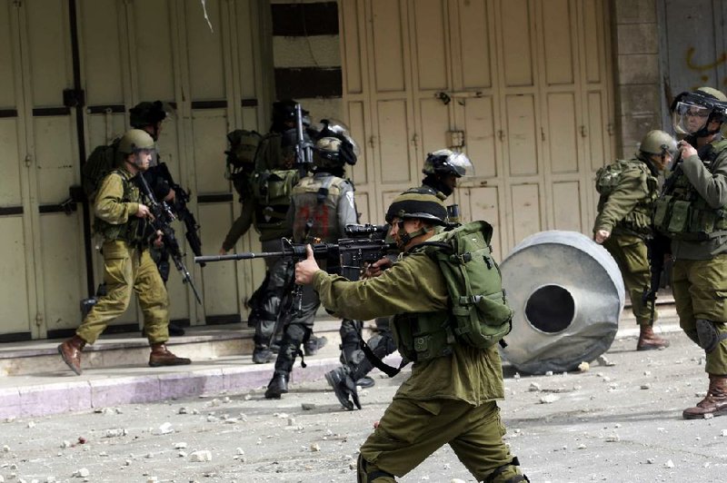 An Israeli soldier takes aim during clashes Sunday in the West Bank city of Hebron after the death of a Palestinian prisoner held in an Israeli jail. 