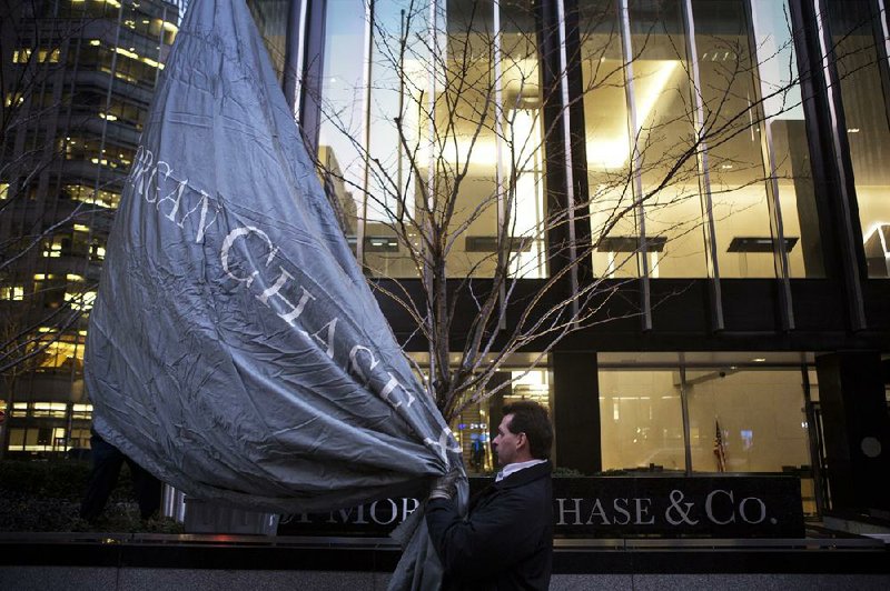 Workers raise a JPMorgan Chase & Co. flag at company headquarters before an annual Investors Day conference in New York, U.S., on Tuesday, Feb. 26, 2013. JPMorgan Chase & Co., the biggest U.S. bank, expects headcount to decline by about 4,000 in 2013 as Chief Executive officer Jamie Dimon targets mortgage operations for cuts. Photographer: Victor J. Blue/Bloomberg