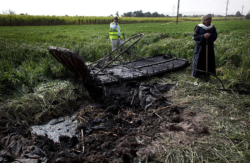 An Egyptian inspector of the Civil Aviation Authority, left, works at the site of the balloon accident, in Luxor, Egypt, Tuesday, Feb. 26, 2013. A hot air balloon flying over Egypt's ancient city of Luxor caught fire and crashed into a sugar cane field on Tuesday, killing at least 19 foreign tourists in one of the world's deadliest ballooning accidents and handing a new blow to Egypt's ailing tourism industry. (AP Photo/Nasser Nasser)