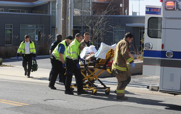 Central Emergency Service and Fayetteville Fire Department personnel work Feb. 8 with University Police Department officers to load student Matthew Williamson into an ambulance after an accidental self-inflicted gunshot wound to his hand at the KUAF studio on School Avenue in Fayetteville. 