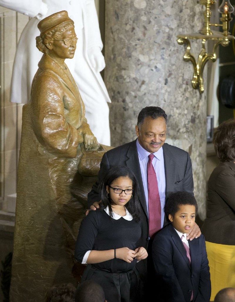 Under a statue of Rosa Parks, civil rights activist Rev. Jesse Jackson poses for photo with his grandchildren, Jessica Donatella Jackson, left, and Jesse Louis Jackson III, right, on Capitol Hill in Washington, Wednesday, Feb. 27, 2013, where President Barack Obama took part in a ceremony where the statue was unveiled.  (AP Photo/J. Scott Applewhite)