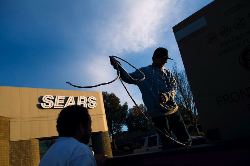Customers secure a new washing machine outside a Sears store in Richmond, Calif., on Tuesday. Sears on Thursday reported a loss of $489 million in the fourth quarter that ended on Feb. 2. 