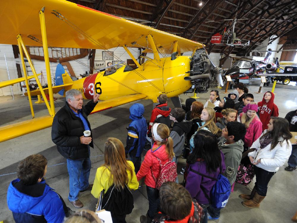 NWA Media/ANDY SHUPE
Warren Jones, executive director of the Arkansas Air and Military Museum in Fayetteville, left, speaks to a group of gifted and talented program students from Kirksey Middle School in Rogers Thursday, Feb. 28, 2013, beside a World WAr II-era Boeing Stearman N2S-2 during a tour of the museum. The visit is a part of the group's Common Core unit called 