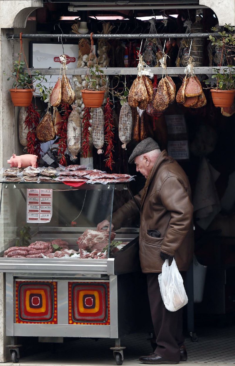 A customer inspects a cut of meat at a butcher shop in Genzano, Italy, on Friday. Eurozone unemployment rose to 11.9 percent in January, up from 11.8 percent in December. 