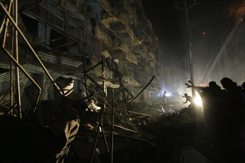 Pakistanis check the site of a bomb blast in Karachi, Pakistan, Sunday, March 3, 2013. Pakistani officials say a bomb blast has killed dozens of people in a neighborhood dominated by Shiite Muslims in the southern city of Karachi.