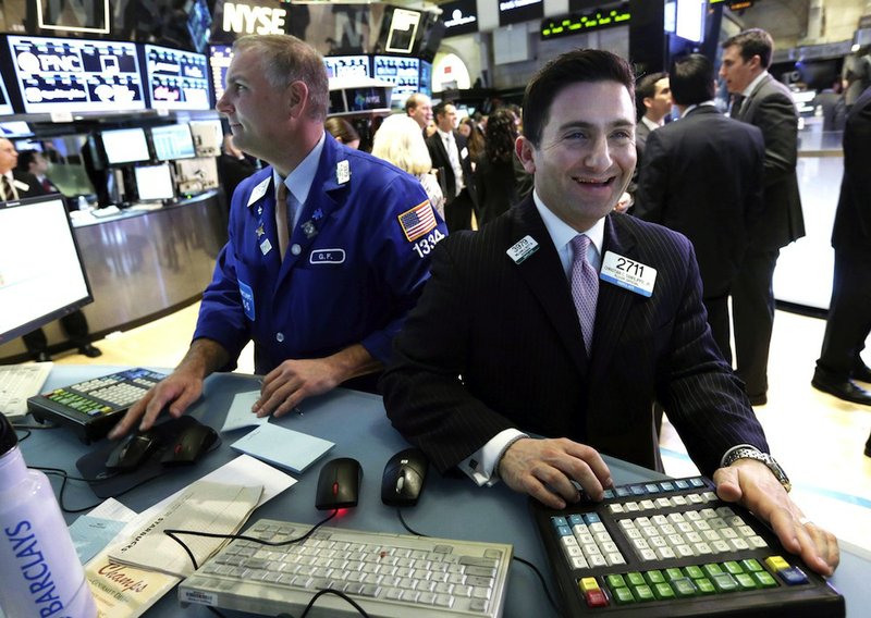 FILE - In this Tuesday, March 5, 2013, file photo, specialist Christian Sanfillippo, right, smiles as he works at his post on the floor of the New York Stock Exchange. The Dow's new all-time high and better economic data from the United States propelled world stock markets higher Wednesday March 6, 2013. 