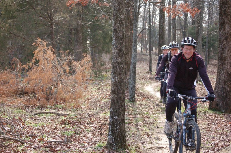 From the front, Steve Lercher, who developed the Lercher 15 Trails in McRae, rides mountain bikes with Jason Morgan and Tanya Lercher, Steve’s wife, along one of the trails on Steve’s family’s property. 