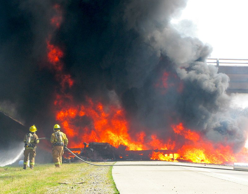 Firefighters work to extinguish a tractor-trailer consumed by fire in a wreck that shut down I-40 Thursday.