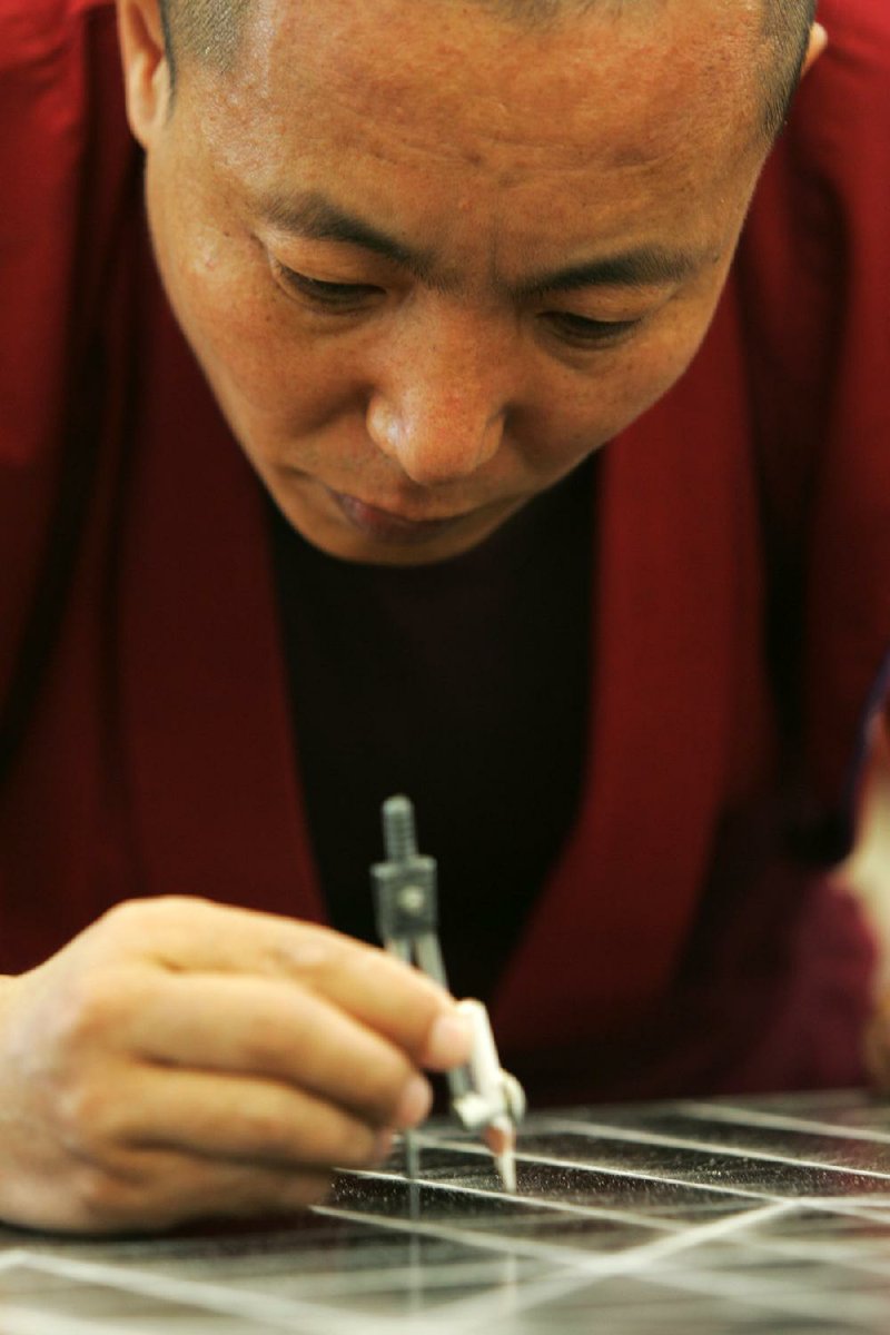 Namgyan Sangpo, a Tibetan monk, works on a mandala at the University of Arkansas at Fayetteville. Mandalas are intricate designs made of colored sand. 