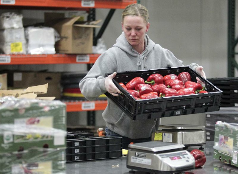 An employee at Organically Grown Co.’s warehouse in Gresham, Ore., sorts bell peppers in February. Inventories at U.S. wholesalers rose 1.2 percent in January, beating economists’ estimates. 